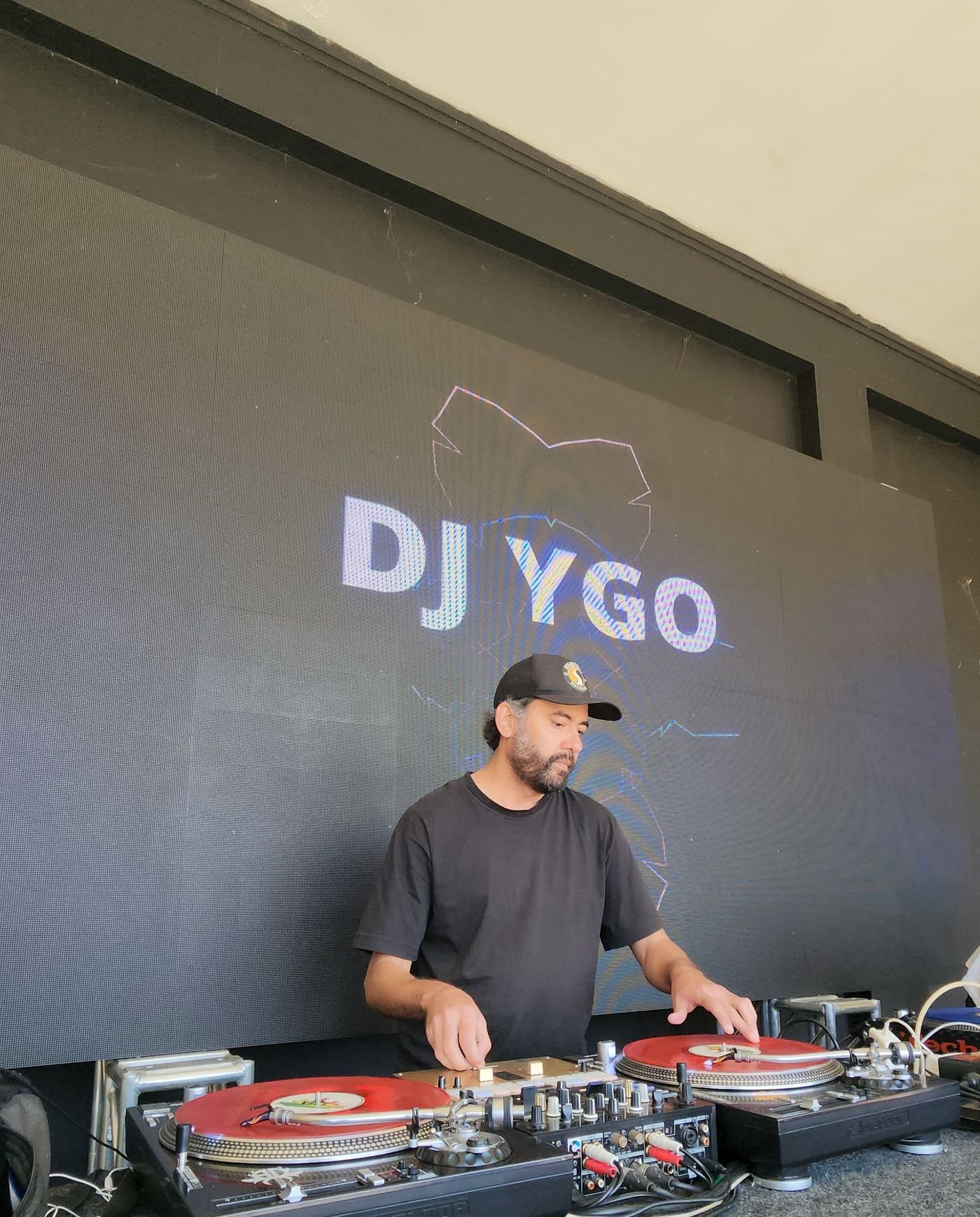 DJ YGO nos giradiscos, com o nome projetado em telão de LED